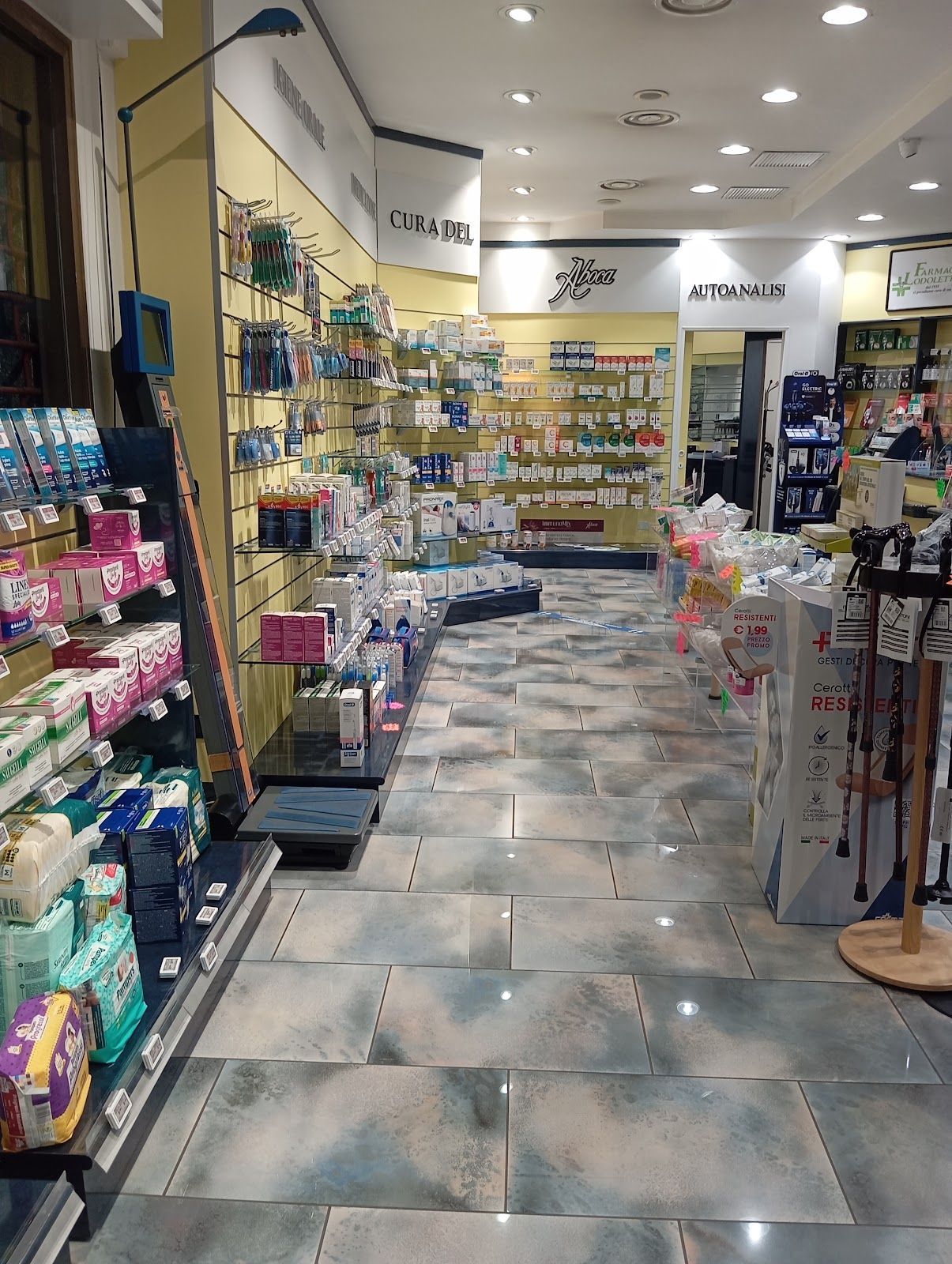 Un corridoio di negozio ben illuminato con scaffali pieni di articoli da toeletta, cosmetici e piccole vetrine.