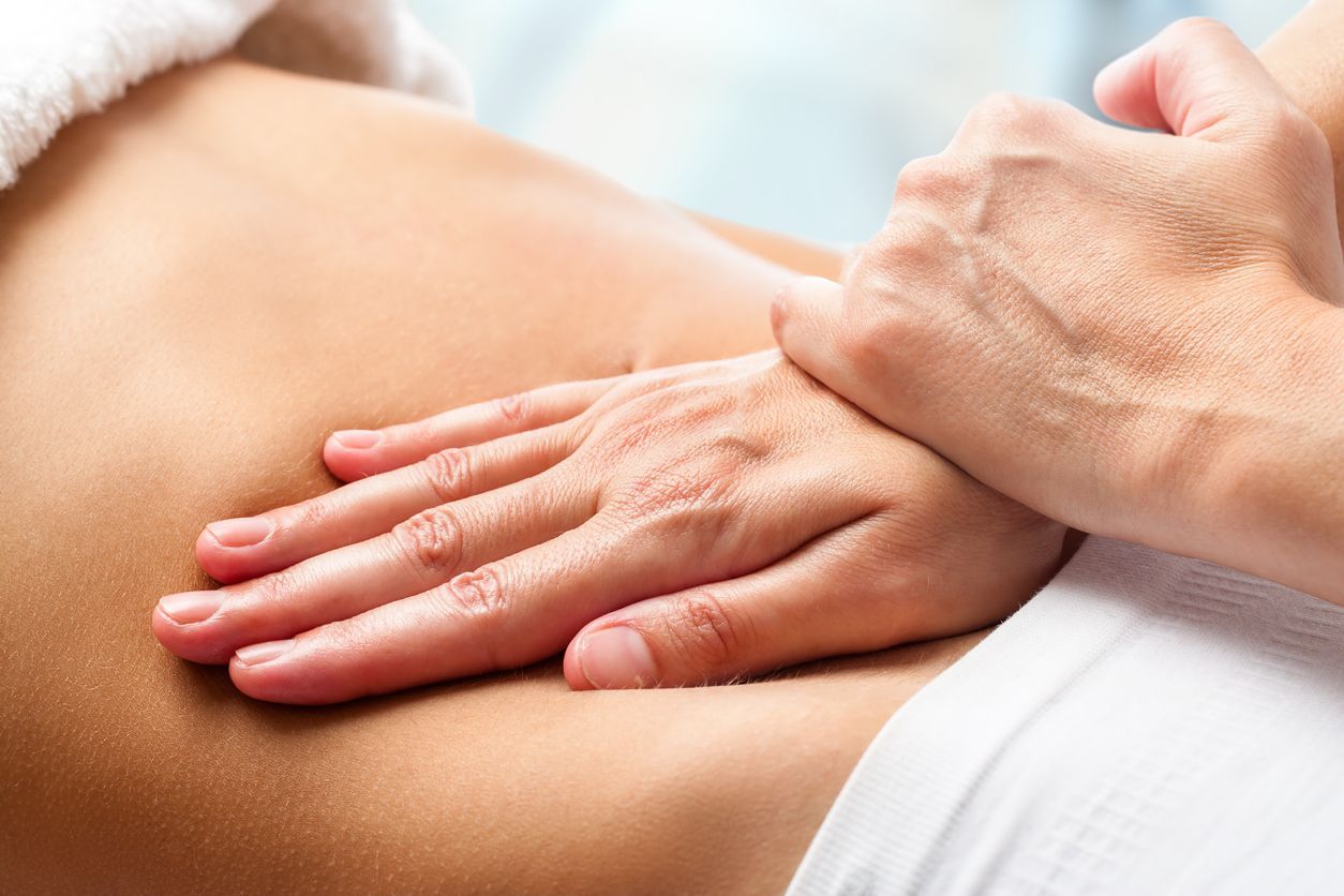 Manos que dan un masaje en la espalda desnuda de una persona con aceite o loción.