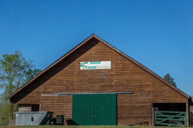 A wooden building with green doors and a Camp Fairview sign