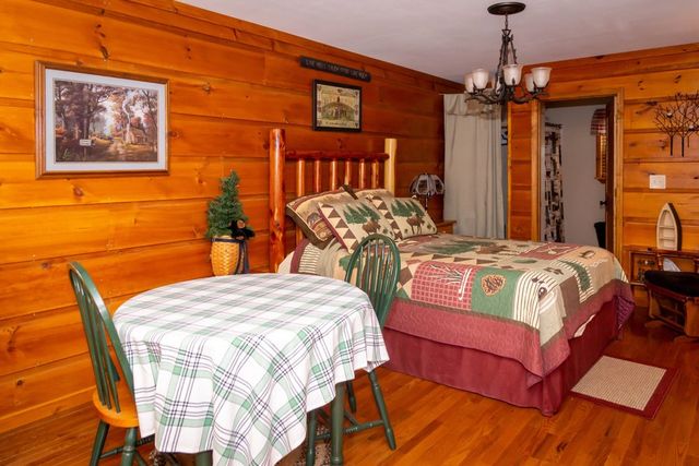 A furnished bedroom with a quilted bed and a small table