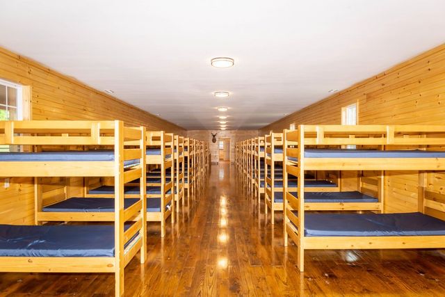 A long bunk room lined with wooden bunk beds on both sides