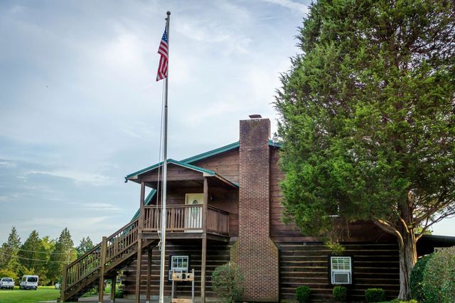 A two-story log building beside a flagpole flying the American flag