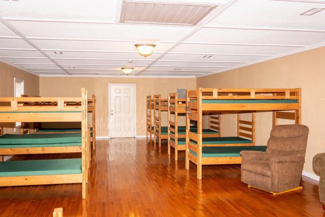 A bunk room with wooden bunks and an armchair