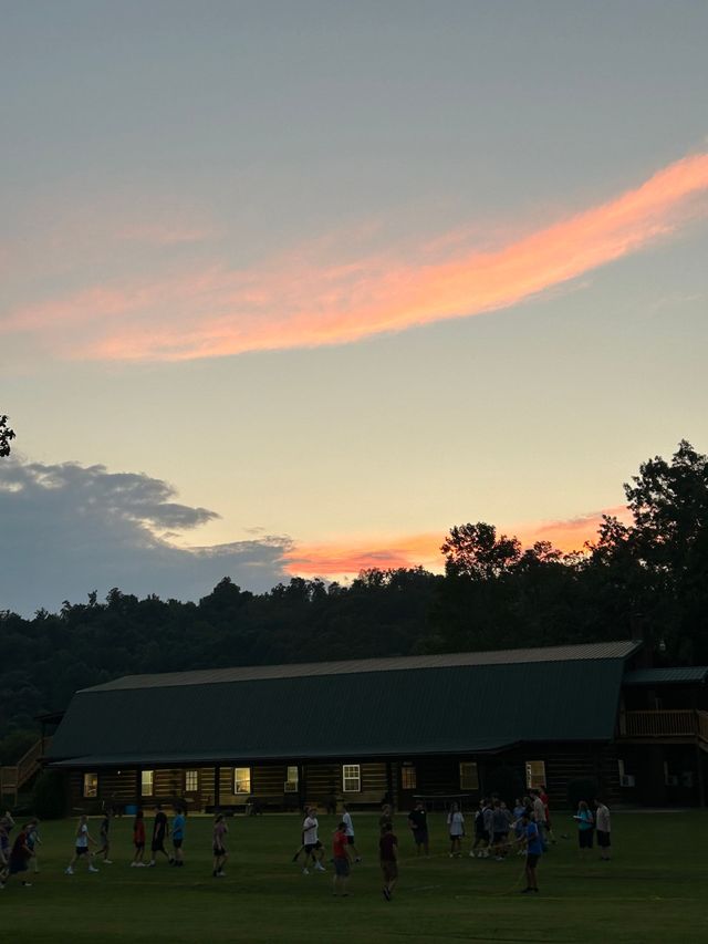 A pink sunset sky over a camp building and field