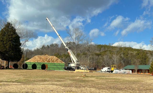 A crane lifting roof trusses onto a new building frame