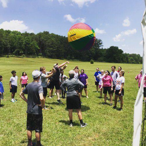 Campers in a field batting a giant inflatable ball