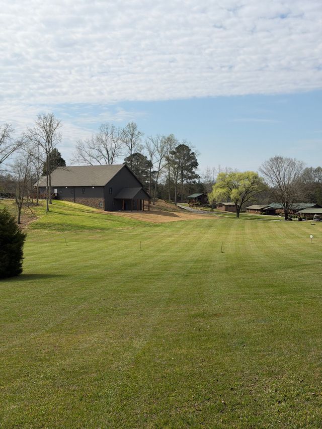 A long mowed field leading toward camp buildings
