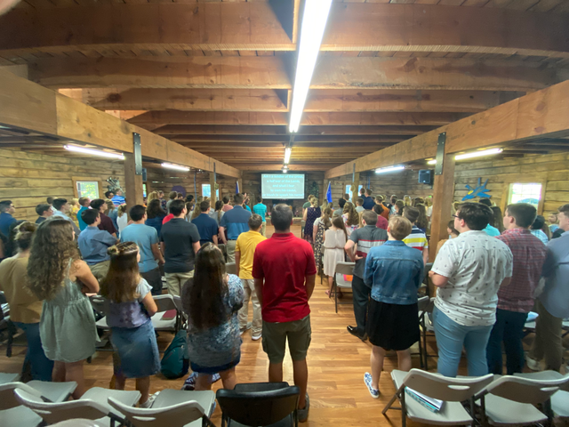 A crowded room of campers standing during a service