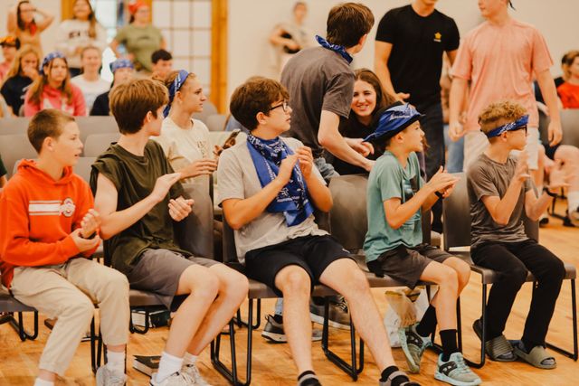 Campers in bandanas clapping and cheering in their seats