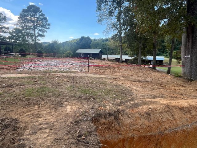 Cleared and graded ground with camp buildings beyond