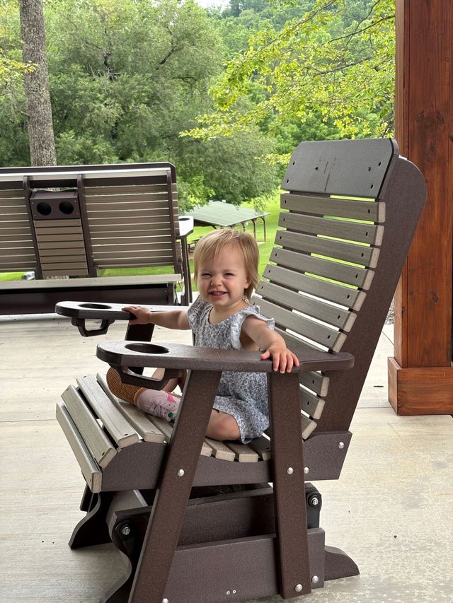A toddler sitting in a rocking chair on the pavilion