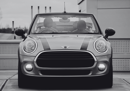 Front view of a MINI Cooper convertible parked in front of a wall, in black and white.