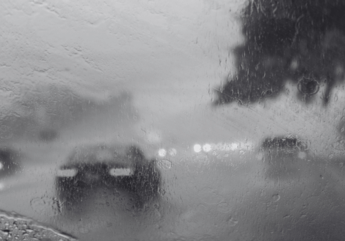 Rainy road seen through a car windshield with blurred vehicles and headlights ahead