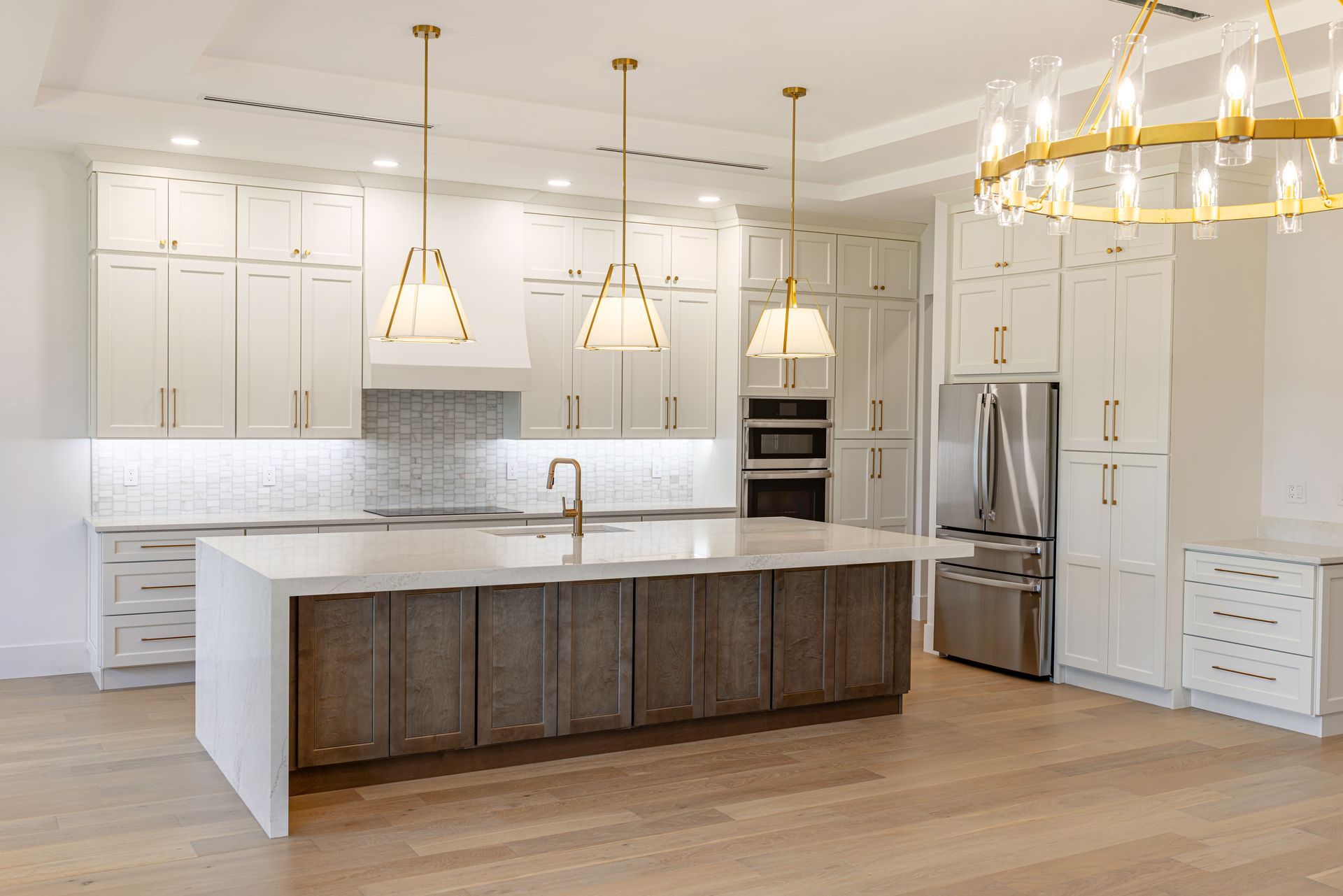 Bright modern kitchen with gray cabinets, white island, stainless steel appliances, and pendant lights Bright modern kitchen with gray cabinets, white island, stainless steel appliances, and pendant lights