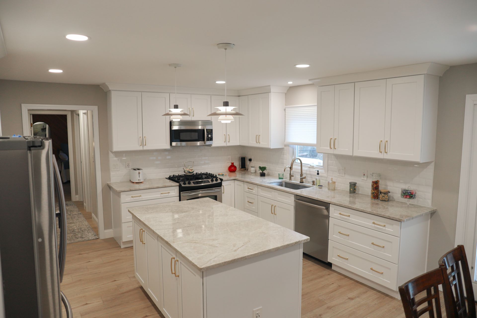 A kitchen with white cabinets, granite counter tops, stainless steel appliances ,and a large island.