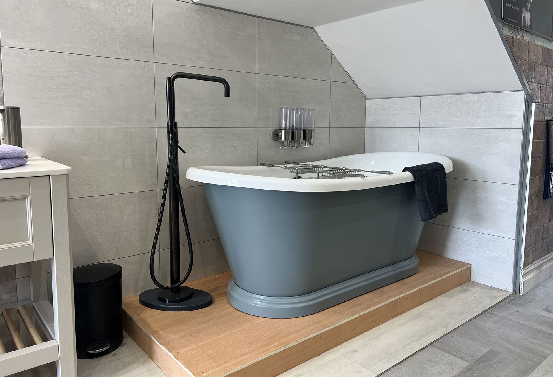 A bathroom with a gray tub and a black faucet
