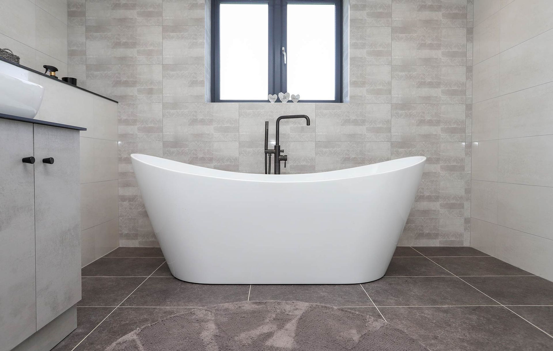A bathroom with a bathtub , sink , and window.
