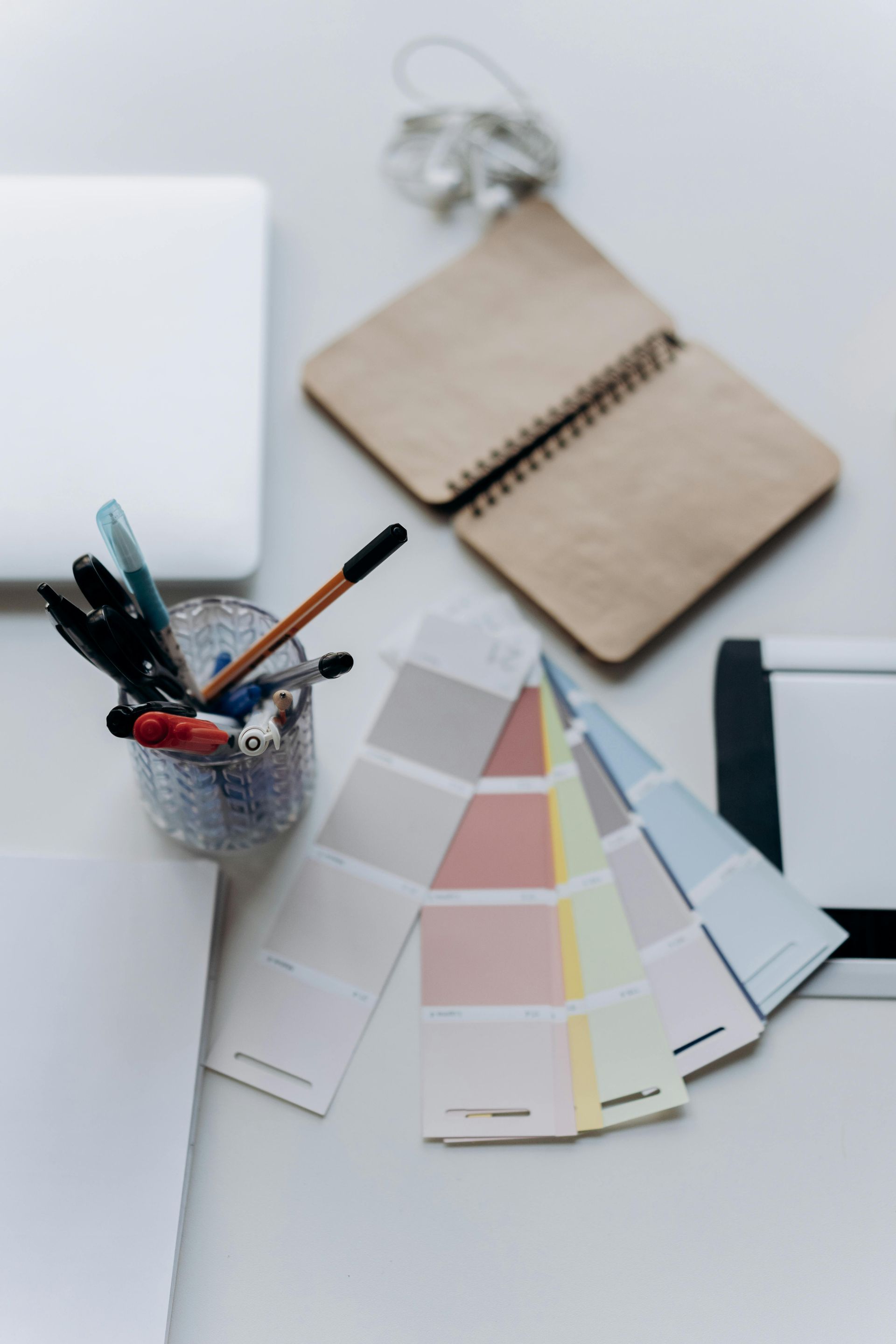 A desk with a laptop notebooks and paint samples