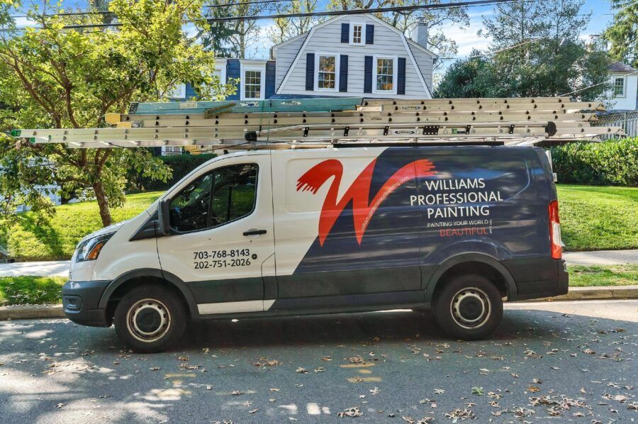 White service van with ladders parked on a tree-lined street in front of a house