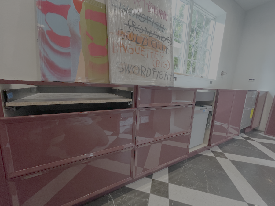 Pink cabinets and wall art in a modern kitchen with a black-and-white checkered floor