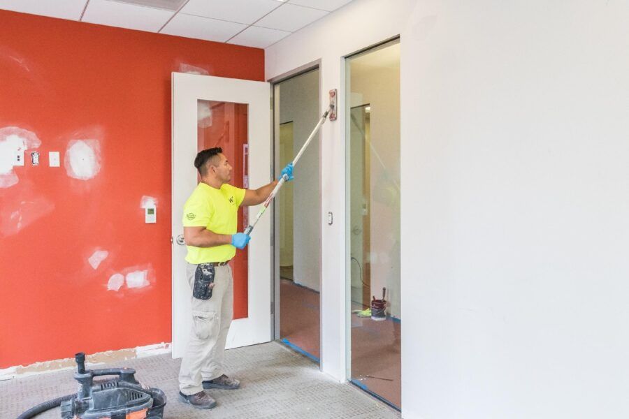 Worker painting a room with a red accent wall and white trim