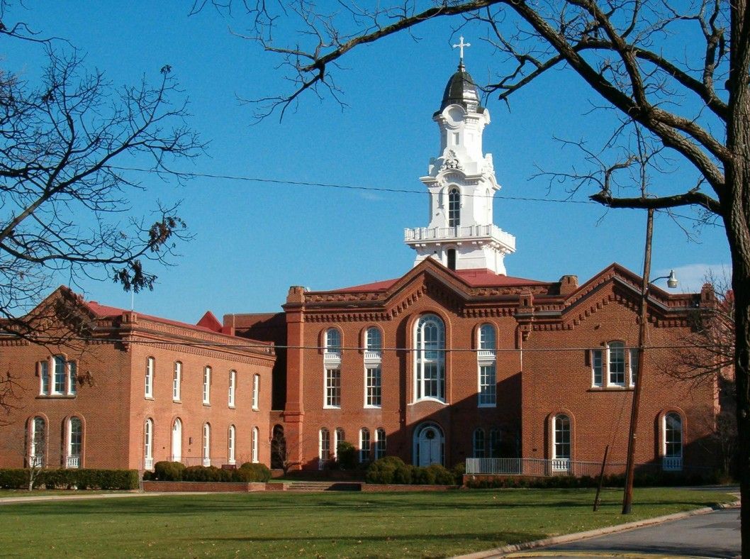 Red-brick courthouse with white clock tower under a blue sky, framed by bare tree branches
