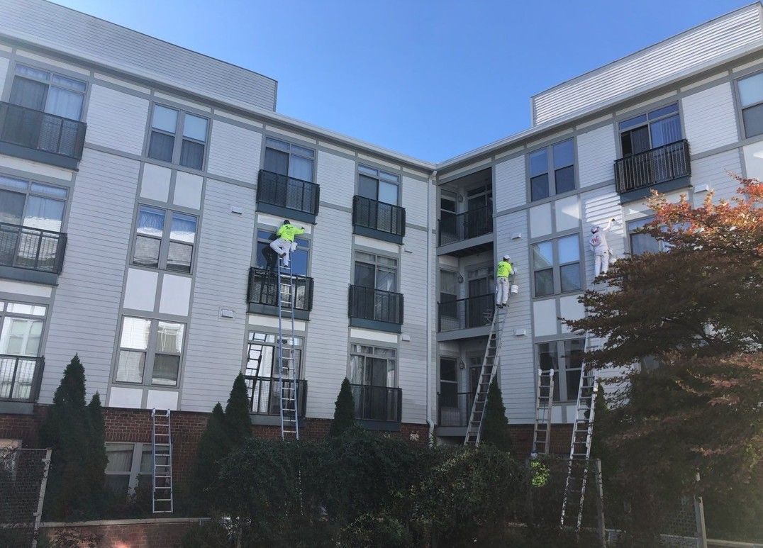 Apartment building with workers hanging from ropes on the facade during exterior maintenance