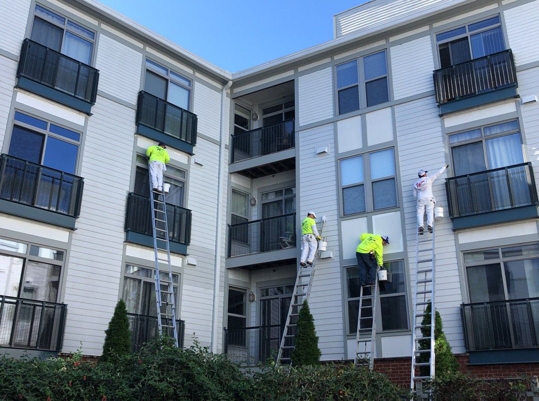 Workers on ladders repairing an apartment building facade and windows