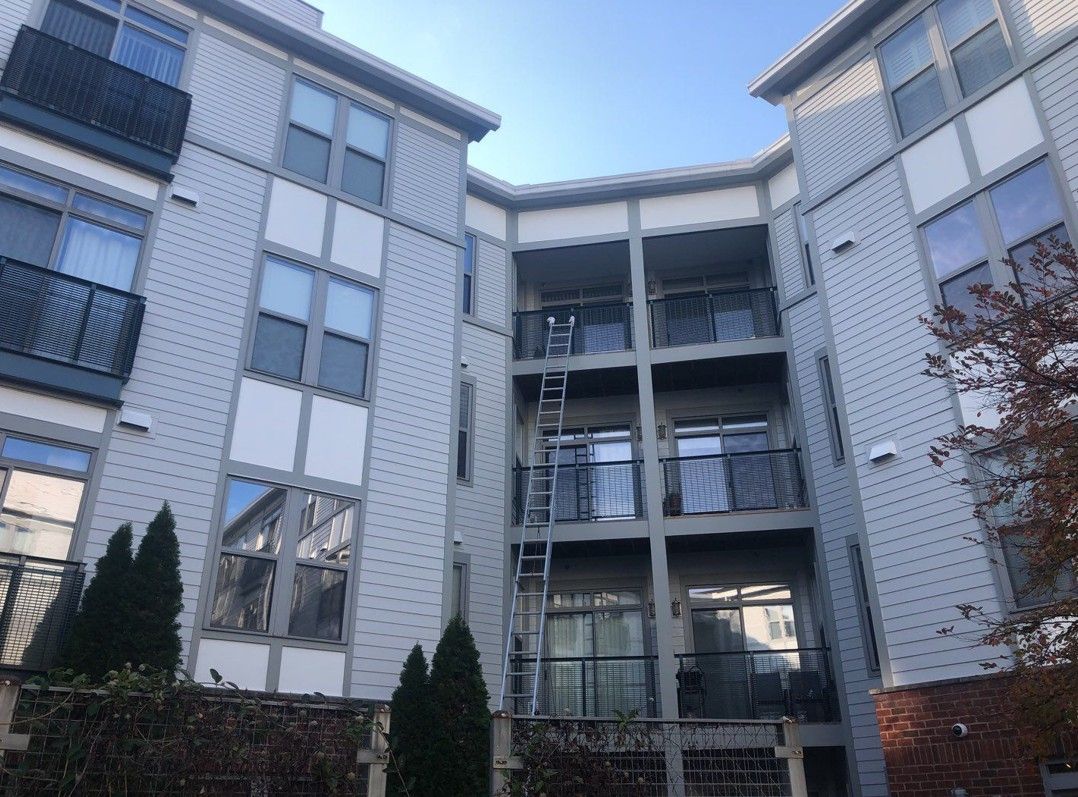 Modern apartment building courtyard with balconies, gray siding, and a clear sky