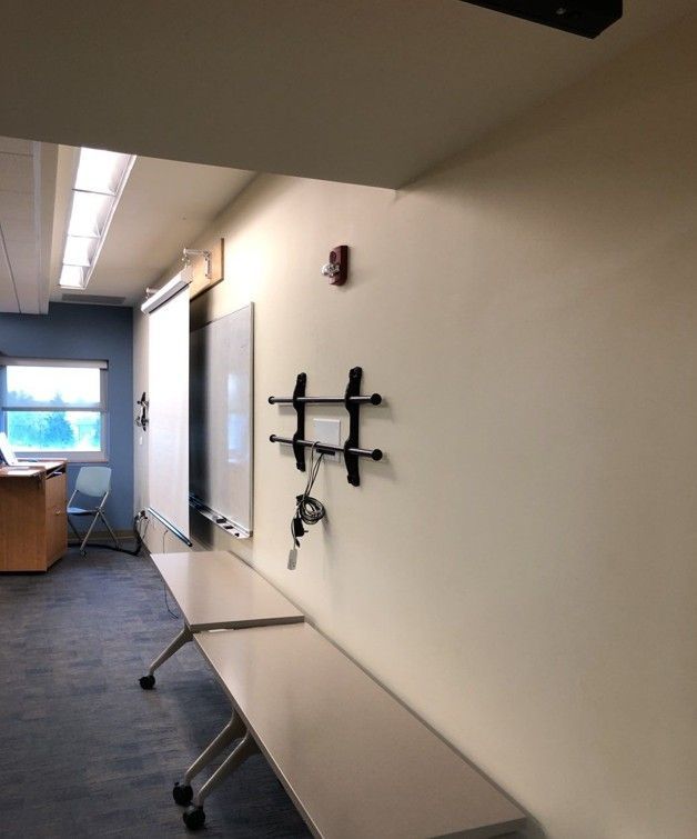 Hallway with wall-mounted TV bracket, long bench, and windows at the far end.