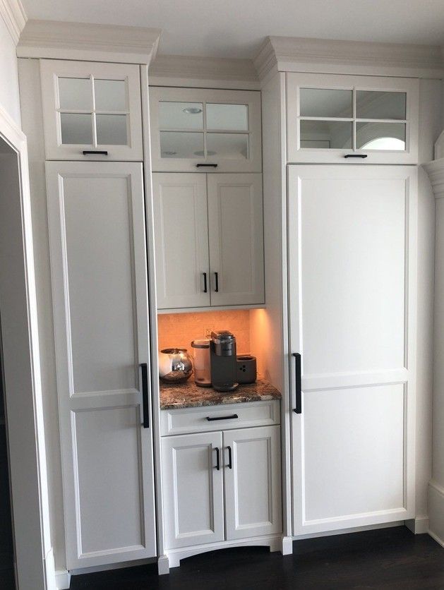 Built-in white kitchen cabinets with a central coffee nook and warm orange under-cabinet lighting