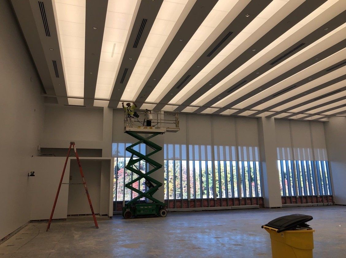 Empty room with a scissor lift under a striped ceiling, and a ladder against the wall.
