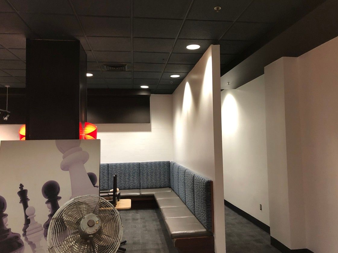 Empty restaurant booth seating with gray benches, white walls, and dark ceiling lights