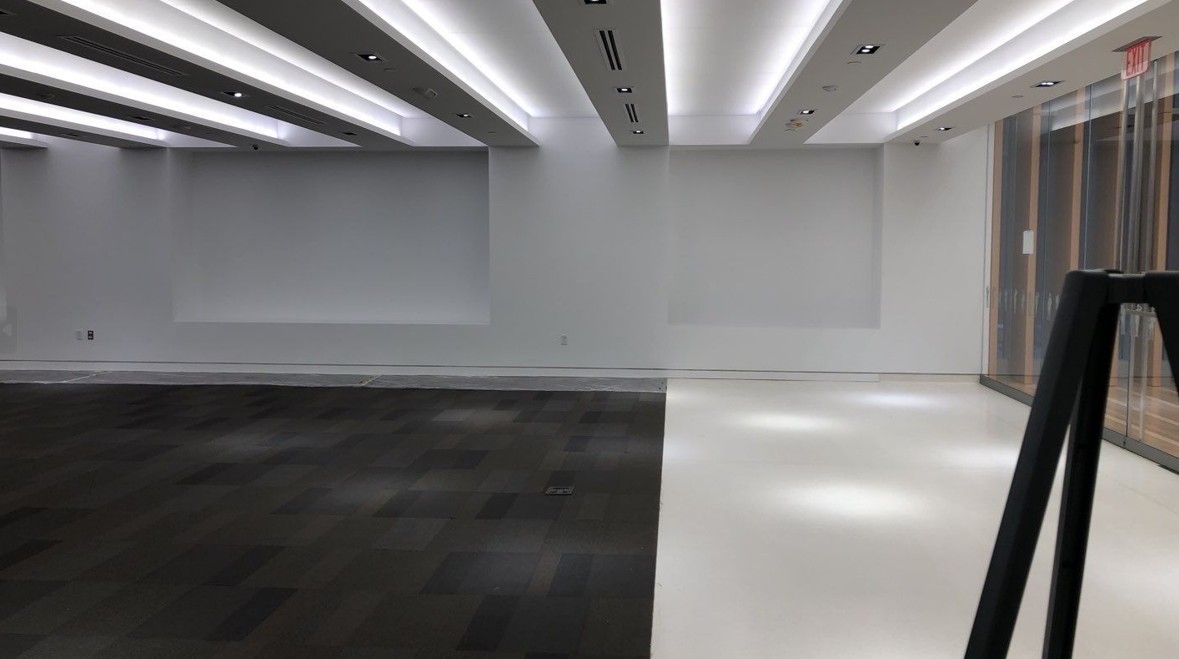Empty modern room with white walls, dark floor section, and recessed ceiling lights