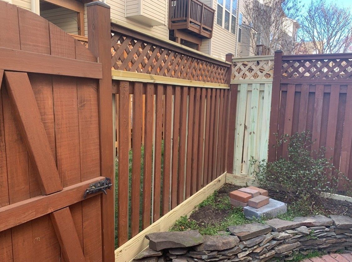 Wooden backyard fence with lattice panels and a small stone garden corner