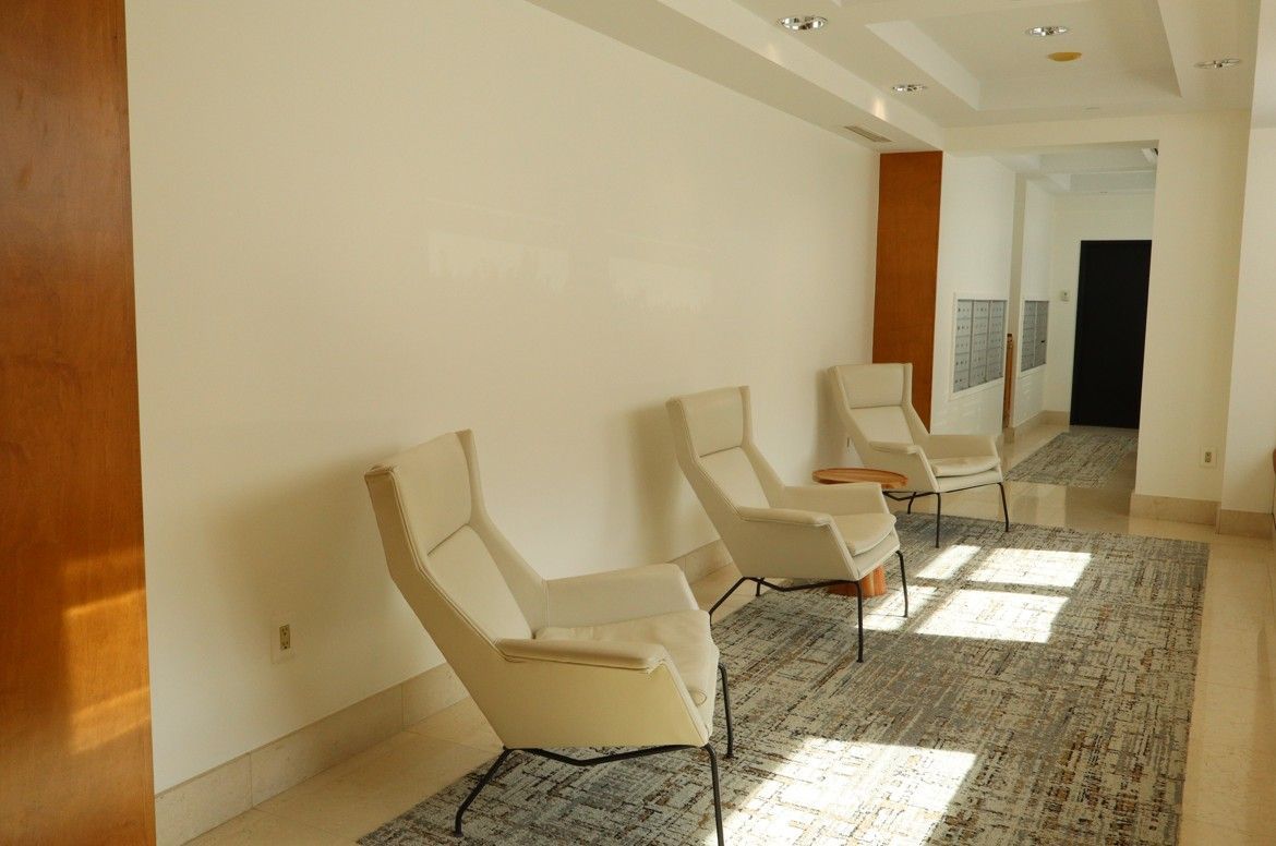 Bright hallway with cream lounge chairs, patterned rug, and sunlight on the floor