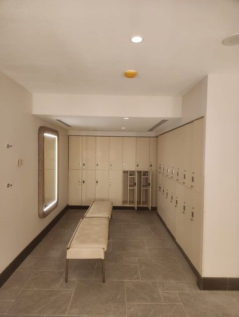 Bright locker room with beige benches, lockers, and tiled floor.