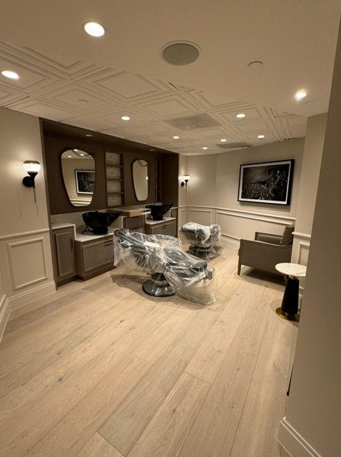 Modern dental treatment room with chair wrapped in plastic, mirrors, cabinetry, and warm recessed lighting