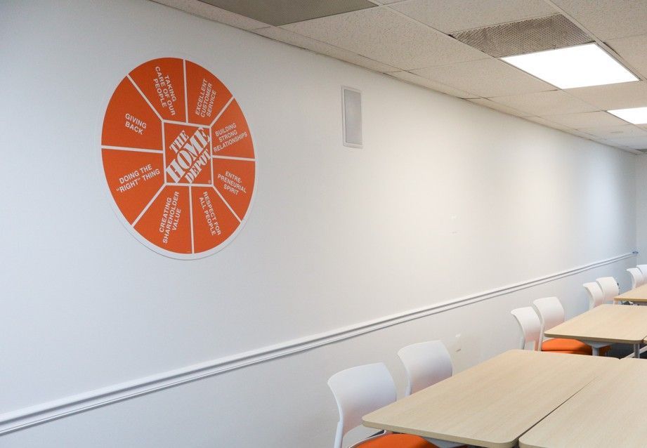 Empty classroom with orange circular wall chart and rows of desks and chairs along the right wall