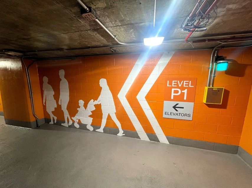 Orange underground parking wall with pedestrian silhouettes, arrows, and a Level P1 sign