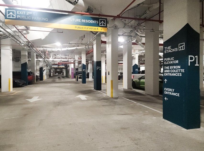 Indoor parking garage with white pillars, parked cars, and a dark teal P1 parking sign