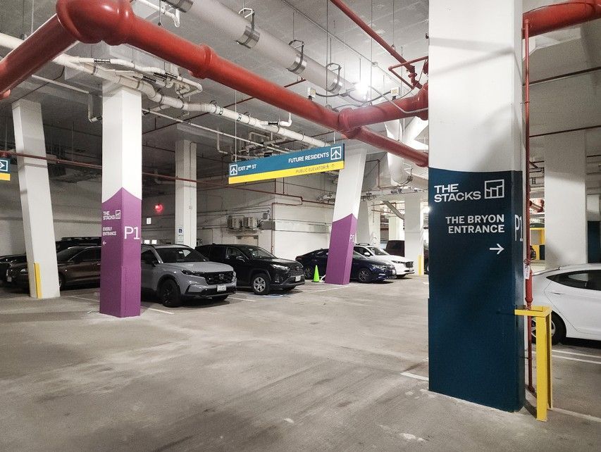 Underground parking garage with parked cars, white pillars, and red pipes overhead