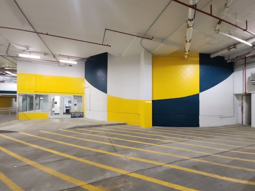 Empty parking garage with yellow lane markings and bold yellow, white, and navy wall panels