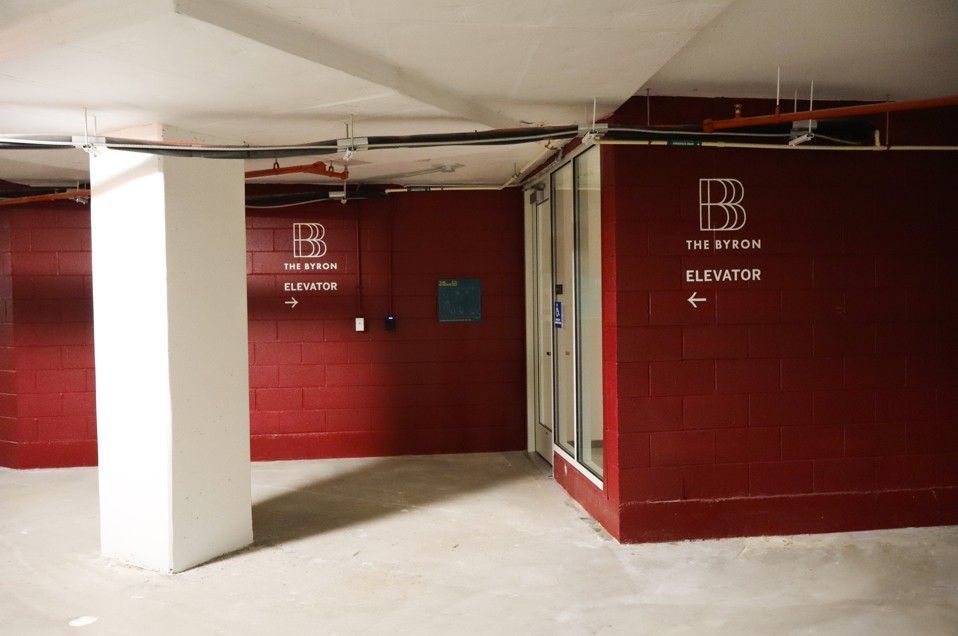 Red parking garage stairwell with a white pillar and an elevator sign on a maroon wall.