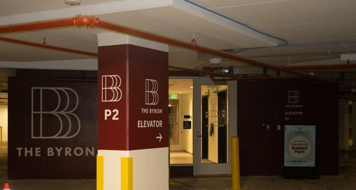 The Byron parking garage entrance with maroon pillars and illuminated signage at night