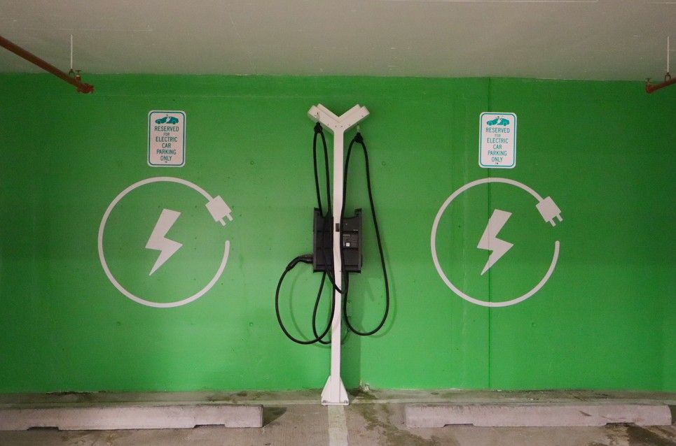Green EV charging station with two wall-mounted chargers and white lightning symbols under a shelter