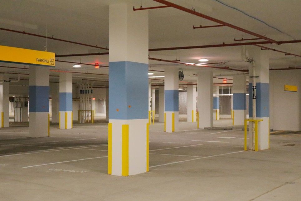 Empty indoor parking garage with concrete pillars painted blue and yellow markings.
