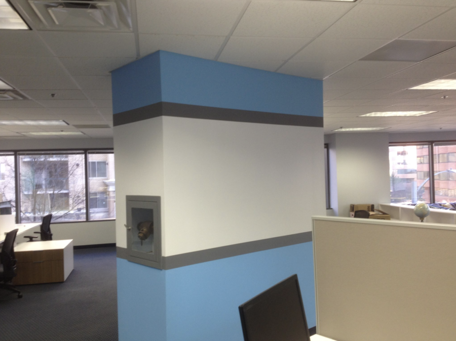 Office interior with blue-and-white columns, desks, and large windows.