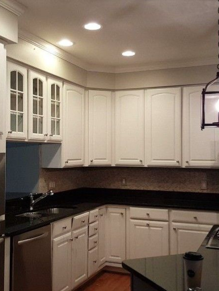 Modern kitchen with white cabinets, black countertops, and recessed ceiling lights