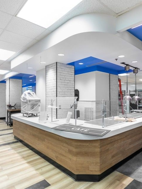 Clean, modern food counter with a white and wood finish in a bright cafeteria or deli interior
